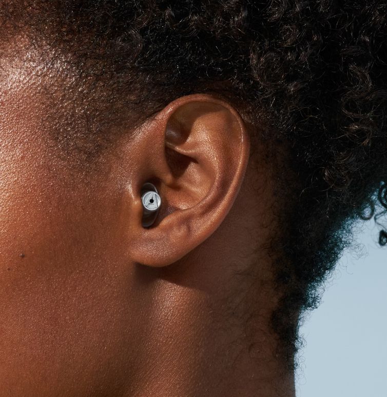 Close-up of a woman’s ear with Alpine earplugs.